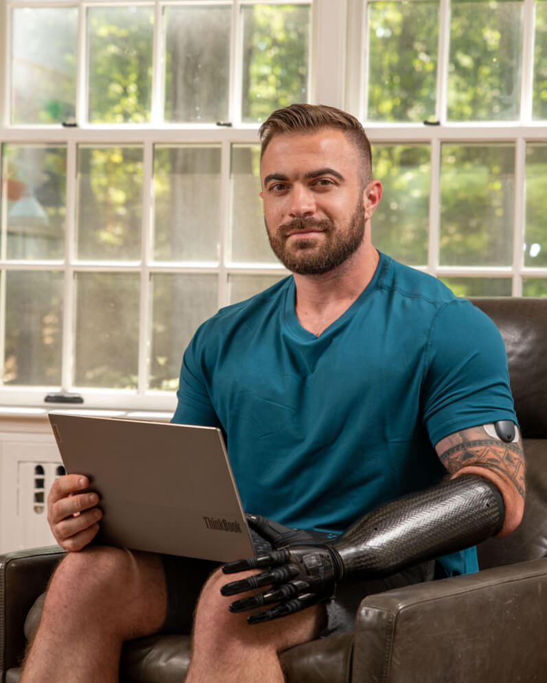 An Eversense CGM user explains the benefits for the transmitter while sitting in a chair 